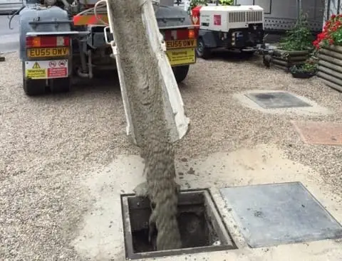 Concrete being gravity fed into a redundant petrol tank.